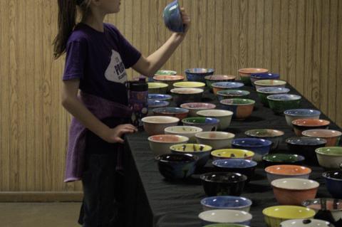 Gabby Garza picks out a hand-crafted bowl from a table full of options during the Elgin Empty Bowl Project event Nov. 13, 2021, in Elgin. Photo by Julianne Hodges