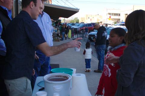 Dan Kleiner at the Elgin Arts Association table hands a cup of hot cocoa to Khaliyah Huerta.